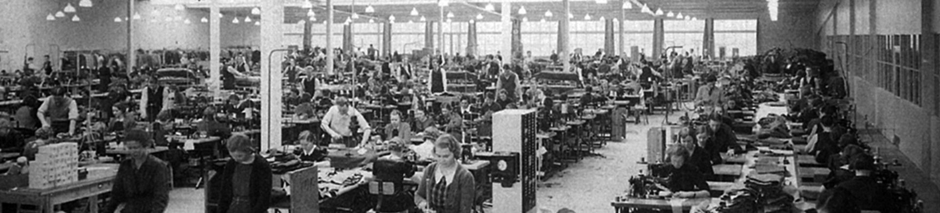 En vy av fabriksarbetare som står och arbetar på ett verkstadsgolv