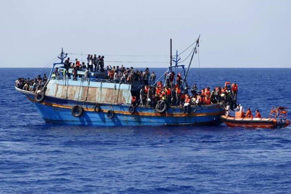 En båt med människor på flykt står tätt på däck.