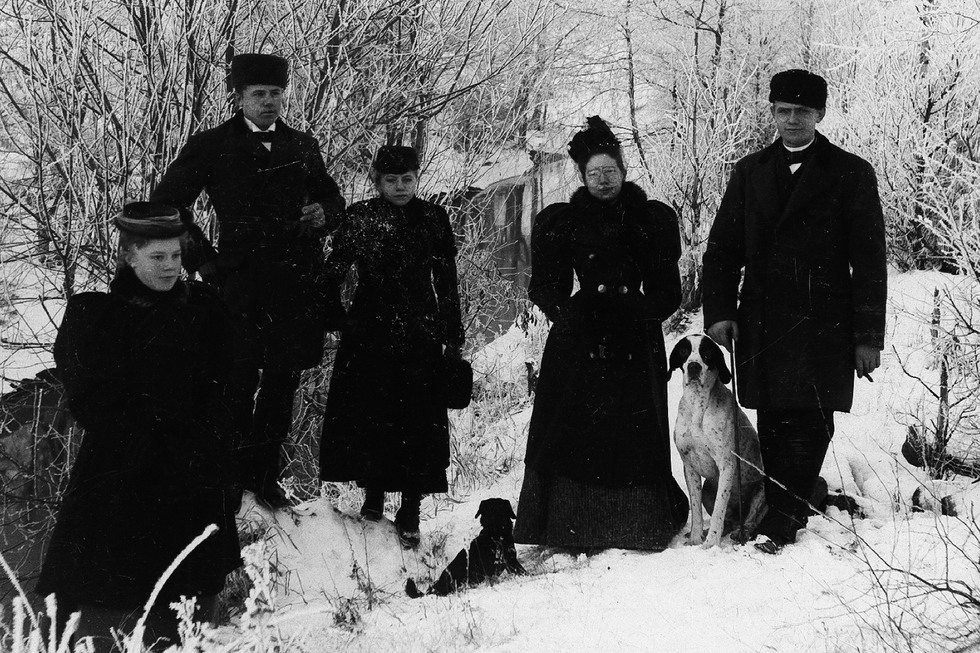 Fem personer och två hundar i vinterlandskap.