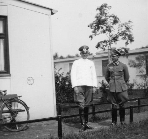 Två uniformsklädda män framför ett hus