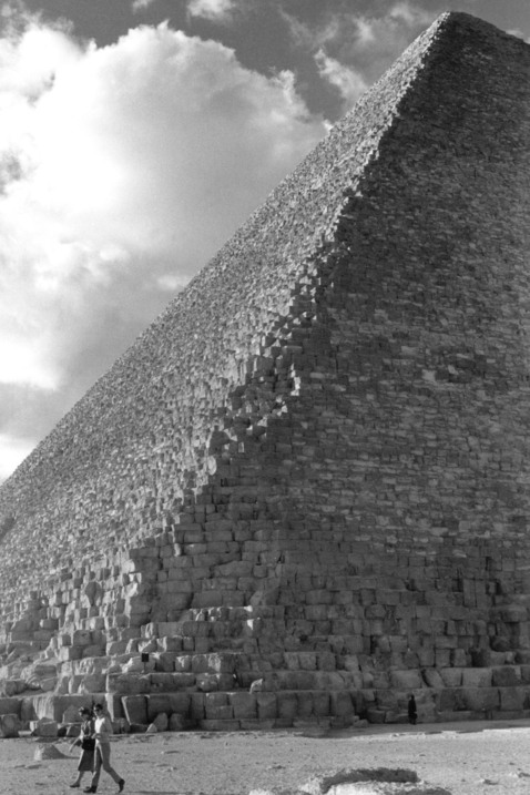 Två personer promenerar framför en stor pyramid