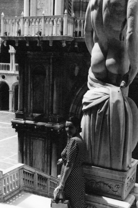 En kvinna poserar framför en skulptur. Venezia, Palazzo Ducale, Scala dei Giganti, Italien.