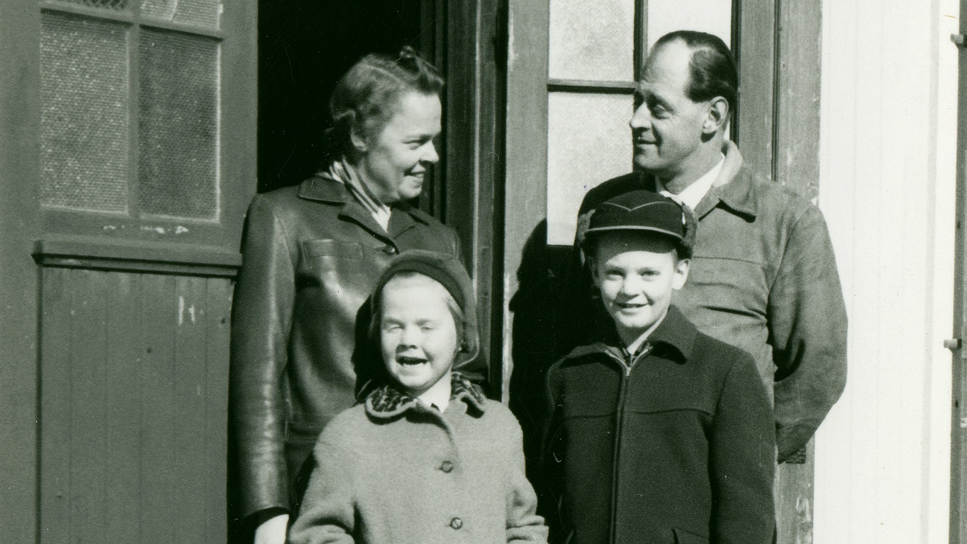 Ruth och Karl Johan ser på varandra med kärleksfull blick, deras två barn står framför dem.