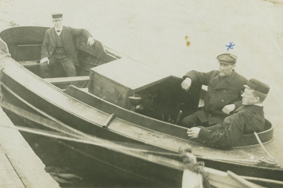 Tre män i en liten motorbåt, 1900-talet.