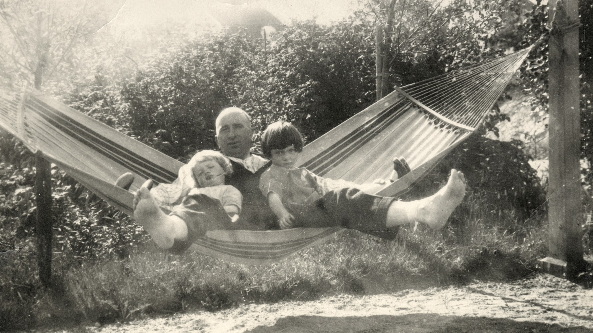 En man och två barn i en hängmatta.