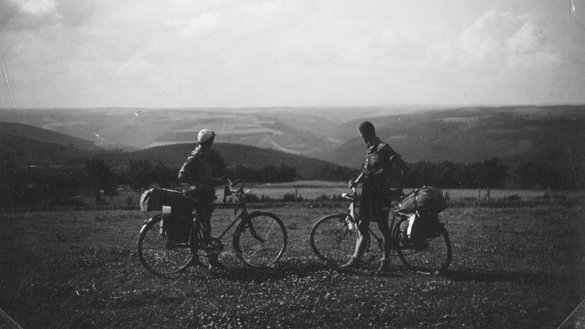 Två cyklister med packning ser ut över ett öppet landskap