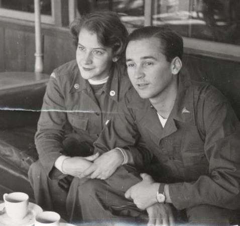 En man och en kvinna sitter i arm i arm med kaffekoppar framför sig.