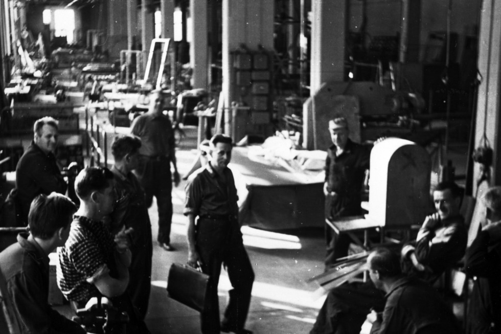 Ett svart-vitt foto inifrån NK:s verkstäder, några arbetare tittar in i kameran. 