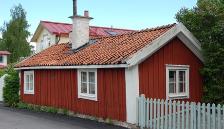 Stuga med röd fasad, vita fönsterkarmar och knutar