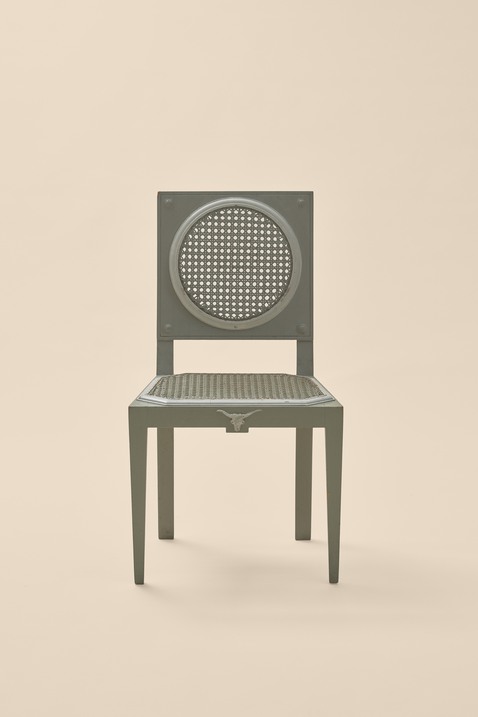 En bild på en grå stol med delar i rotting. 