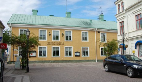 Byggnad med gul putsad fasad och grönt plåttak