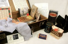 En öppen, brun resväska med böcker, brev och kläder i 